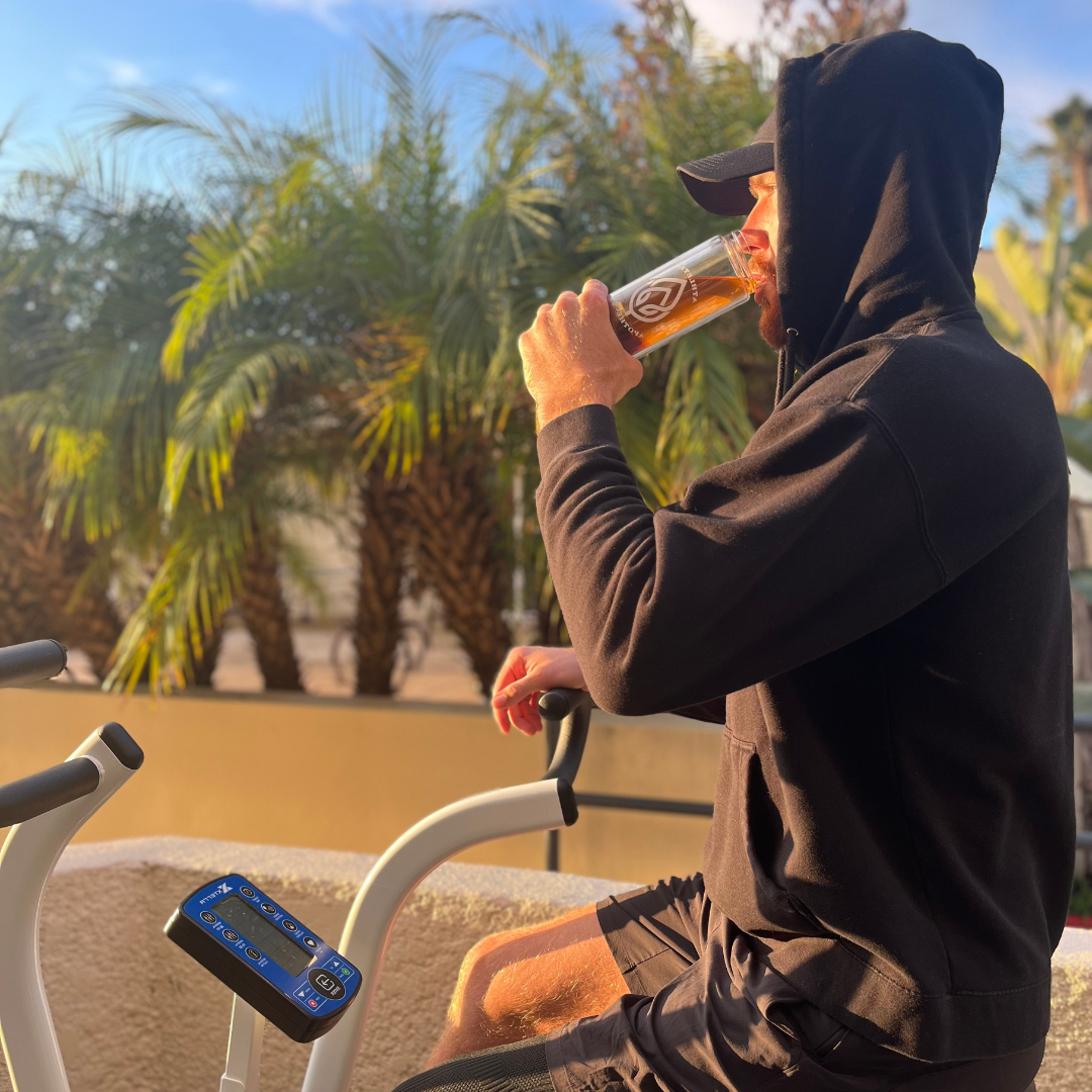Pheonix Copley drinking tea from a tea infusing bottle while riding a bike
