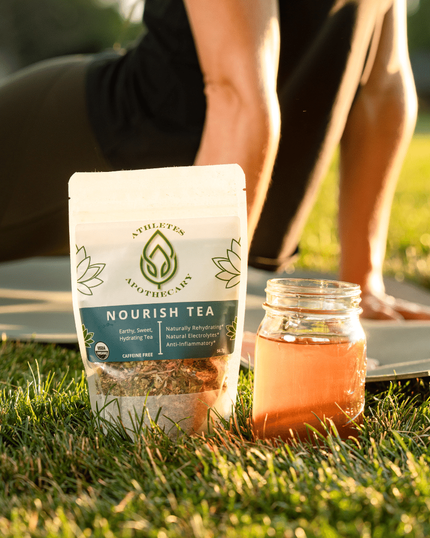 Woman doing yoga with hydrating tea in foreground