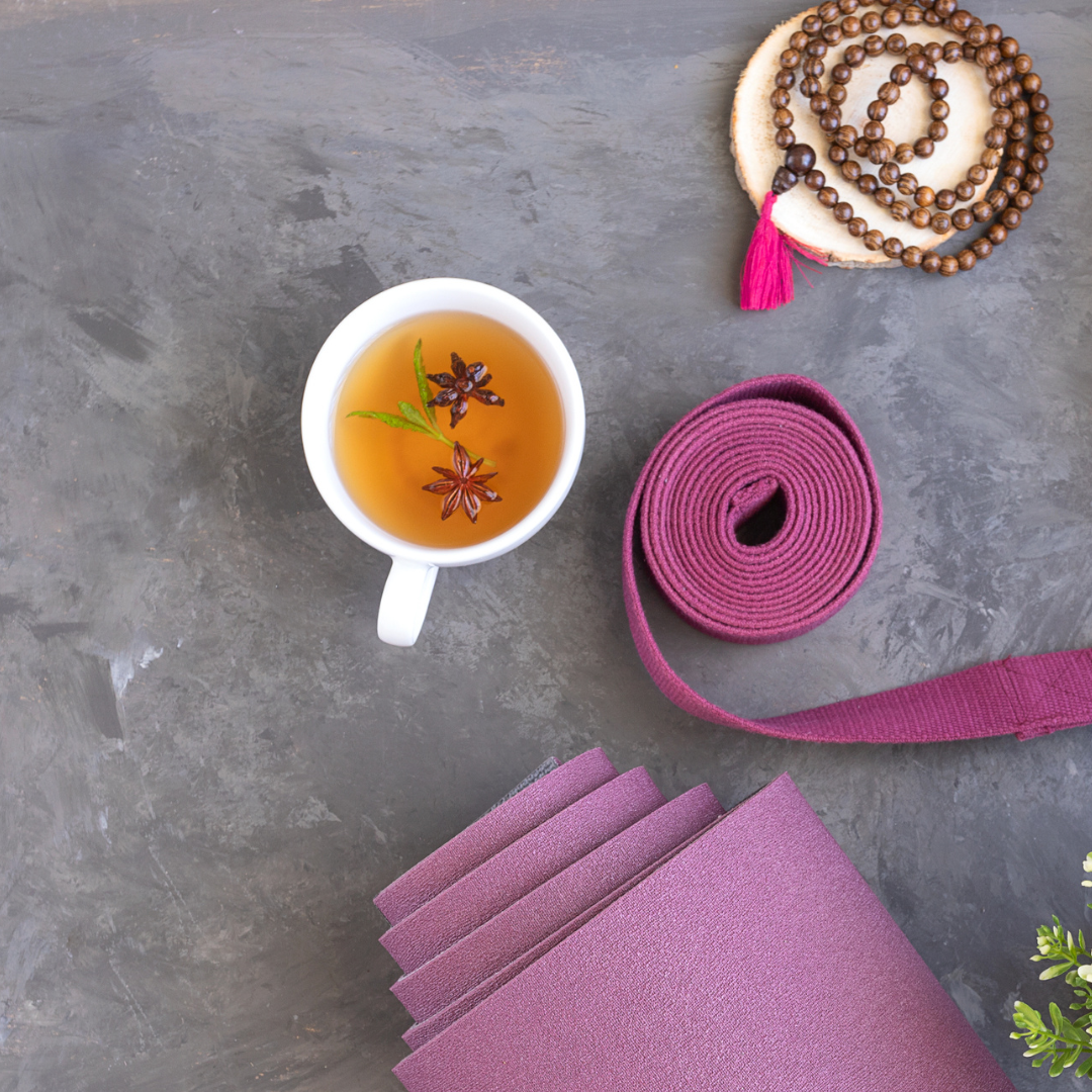 Freshly brewed tea next to a yoga mat and yoga strap