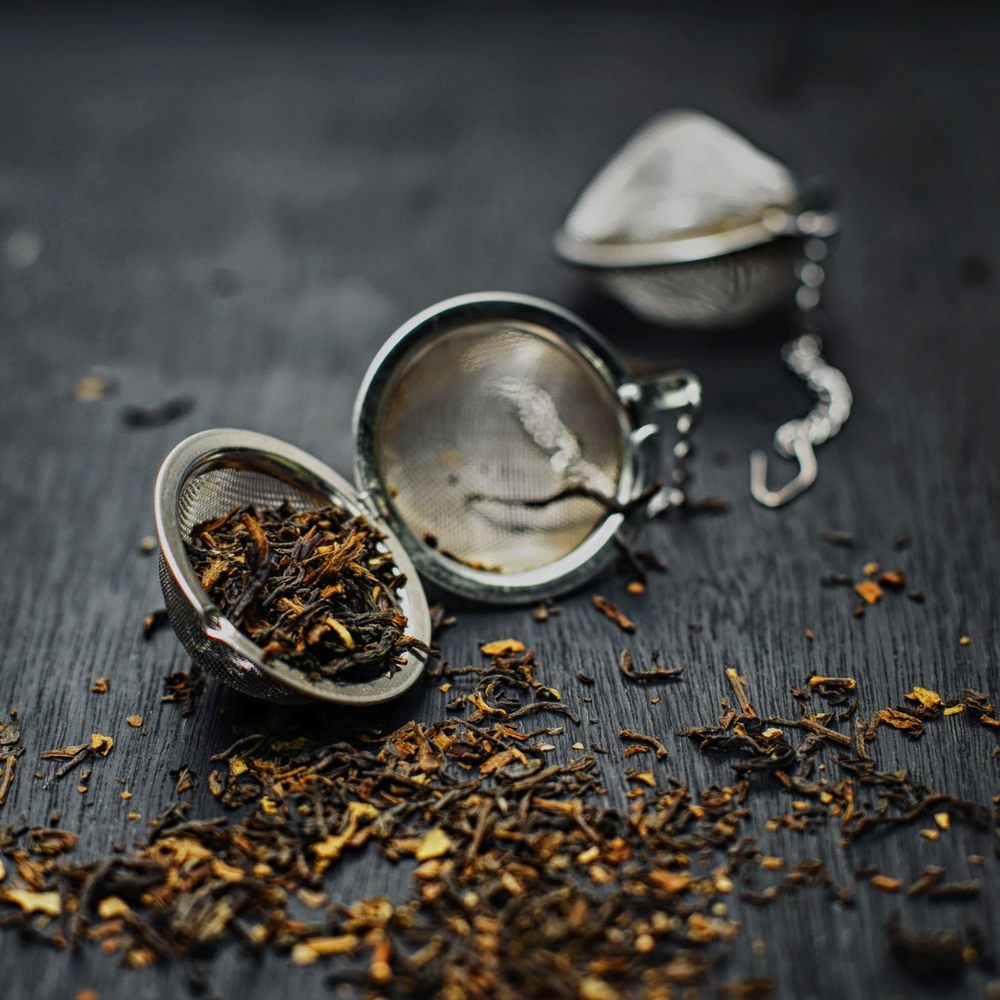 A mesh tea ball with loose leaf tea spilling forth